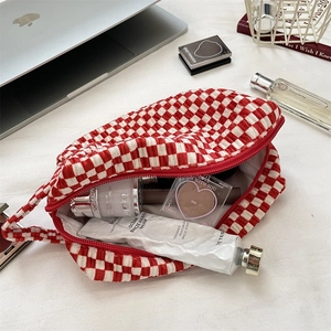 Detailed view of velvet checkerboard makeup bag with skincare items and red zipper