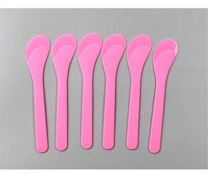 Close-up of six pink plastic facial mask mixing spatulas arranged in parallel