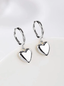 Detailed view of 3D heart-shaped silver earrings with polished mirror finish surface