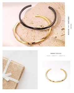 Dettaglio del bracciale aperto a forma di C in oro e nero su uno sfondo di pietra