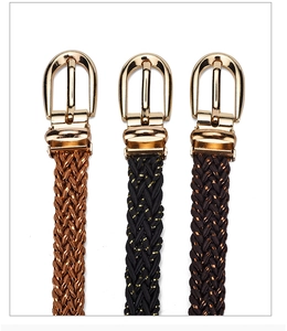 Detail of three woven skinny belts with golden horseshoe buckles for dresses