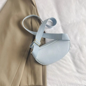 Detail of light blue lychee pattern leather waist bag with golden metal hardware and strap