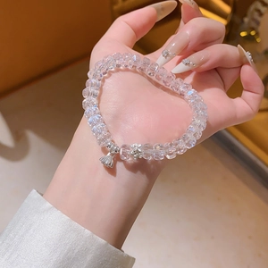 Gros plan d'un bracelet en perles de cristal avec un pendentif fleur de lotus argenté