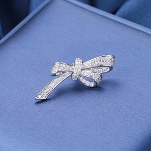 Macro shot of silver bow brooch with sparkling cubic zirconia on a blue background