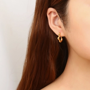 Close-up of a model wearing vintage gold C-shaped stainless steel earrings with lava texture