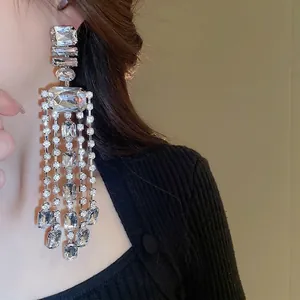 Elegant oversized silver tassel drop earrings with sparkling square crystals on model