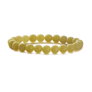 Macro detail of yellow natural stone beads on a single-strand beaded bracelet with smooth texture