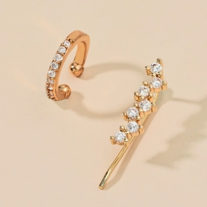 Detail of gold ear cuff and crawler earring set with zircon stones on cream backdrop