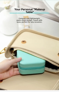 Compact mint green leather jewelry box with zipper being placed inside a stylish handbag