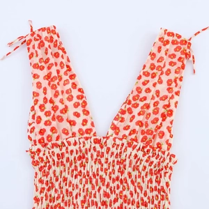 Detail van bloemenjurk met V-hals, strikjes op de schouders en gesmokte elastische taille