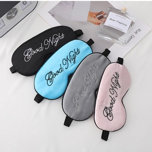Detailed view of silk-like sleep masks in various colors with Good Night embroidery