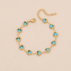 Close-up of golden heart bracelet featuring blue zircon stones and adjustable lobster clasp