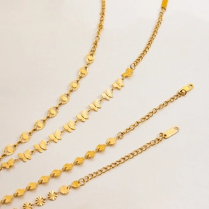 Dettaglio macro dei bracciali in acciaio inossidabile placcato oro 18 carati con girasole e farfalla