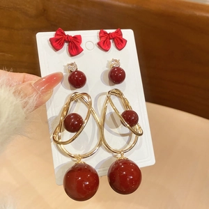 Detail of vintage red bow, pearl, and geometric gold-plated earrings set for women