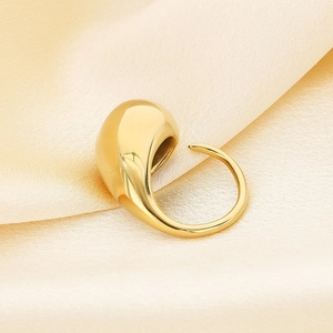 Macro shot of minimalist gold drop ring with high-polish finish on satin fabric