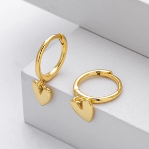 Detailed view of polished gold heart charms on minimalist hoop earrings over a white base