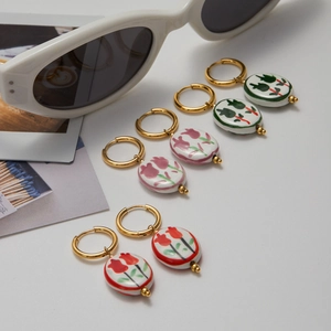 Tre paia di cerchi dorati con pendenti in ceramica a tulipano su sfondo bianco
