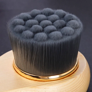 Macro detail of soft grey fiber bristles and light wood handle on a facial cleansing brush