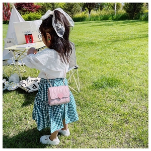 Dettaglio della borsa rosa trapuntata a cuore indossata da una bambina in un giardino