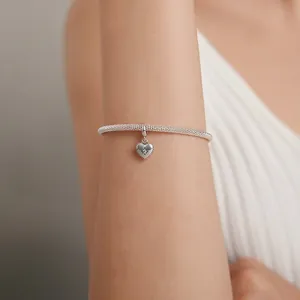 Silver mesh bracelet with starburst heart pendant charm on woman's wrist