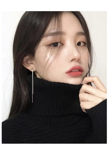 Detail view of long s925 silver tassel earrings worn by a model in black high neck top