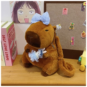 Detail of plush brown Capybara backpack with a blue bow and small bunny doll accessory