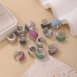 Détails de boucles d'oreilles huggies dorées avec zircons multicolores et motifs ajourés