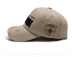 Detail of khaki denim baseball cap with OF CITY embroidery and distressed frayed brim