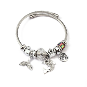 Detailed view of silver charm bracelet with dolphin, tree of life, and crown pendants