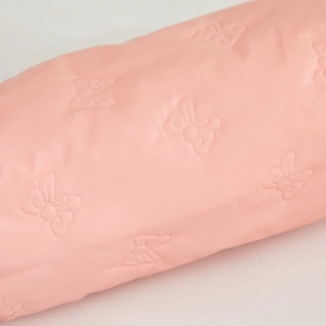 Detail of light pink waterproof PU leather with embossed 3D bow patterns on the makeup bag