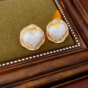 Détail des boucles d'oreilles cœur plaquées or 16K avec perle baroque sur velours vert