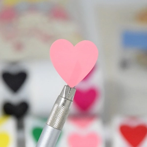 Pink heart shaped stickers roll for DIY decoration showing a precision craft knife detail