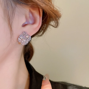 Close-up of a silver geometric cubic zirconia stud earring worn by a model