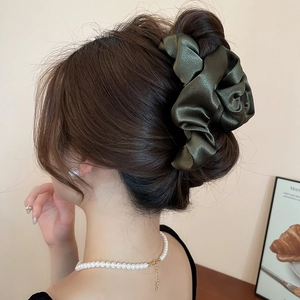 Detailed view of an olive green satin oversized scrunchie worn on a chic bun hairstyle