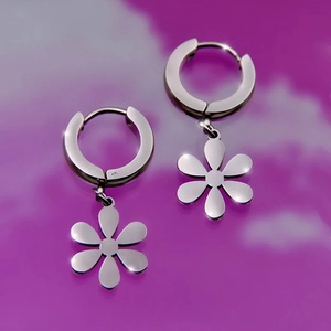 Macro shot of silver stainless steel hoop earrings with polished six-petal flower charms