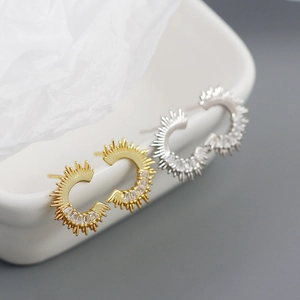 Macro view of C-shaped stud earrings with gold and silver finish and zircon inlay