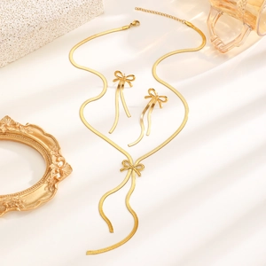 Elegantes Set aus goldener Schleifen-Halskette und Quasten-Ohrringen auf Dekohintergrund
