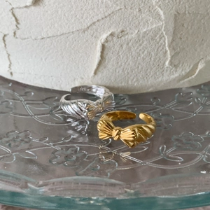 Macro detail of gold and silver S925 sterling silver bow rings on a glass tray