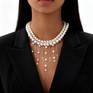Détail d'un collier de perles double épaisseur avec pampilles étoiles et croix argentées