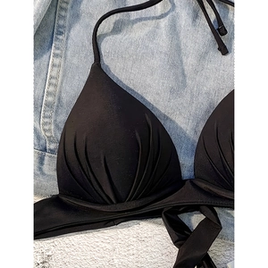 Detail of black halter bikini top featuring pleated cups and high-stretch matte fabric