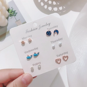 Close-up of 6-pair gold earring set with pearls and blue enamel on white card