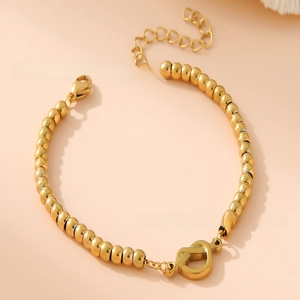 Detailed macro view of 18K gold-plated beaded bracelet with elegant knot clasp and chain