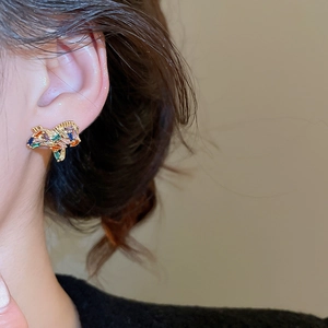 Close-up of gold-plated stud earrings with colorful rectangular cubic zirconia crystals