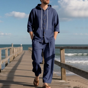 Detail of navy blue linen men's hooded shirt and pants set on a seaside wooden boardwalk