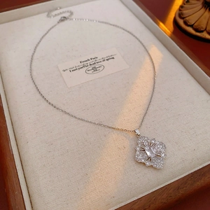 Détail macro d'un collier fleur en argent avec zircon marquise dans un plateau en bois