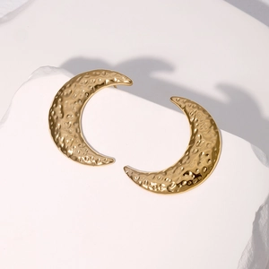 Textured gold crescent moon stud earrings with hammered finish on white stone base
