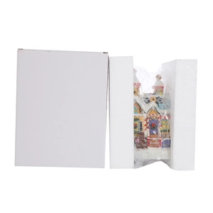 Detailed view of LED snow scene gingerbread house ornament in secure foam packaging