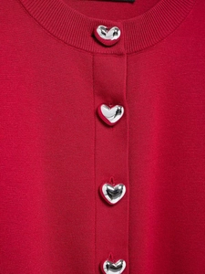 Detailed close-up of vibrant red knit cardigan featuring metallic silver heart buttons