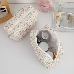 Close-up of pink floral cosmetic bags with heart zipper pulls on a vanity desk