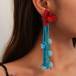 Detail of bohemian long tassel earrings with red fabric flower and sky blue seed beads